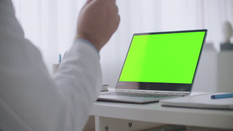 Online-Beratung-Mit-Arzt-Laptop-Mit-Grünem-Bildschirm-Für-Chroma-Key-Technologie-Auf-Dem-Tisch-Und-Gestikulierenden-Händen-Des-Arztes